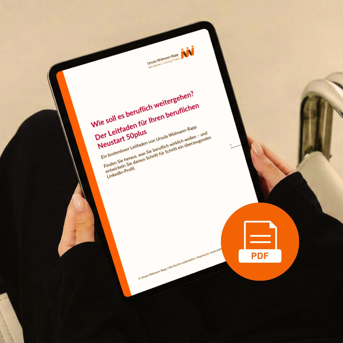 Tabletansicht Leitfaden beruflicher Neustart 50plus Tabletansicht mit Deckblatt des Freebies Leitfaden beruflicher Neustart 50plus. Das Tablet befindet sich in den sorgfältig manikürten Händen einer Frau und ruht auf ihren Oberschenkeln, Kleidung schwarz, Stuhl schwarz, PDF orange und weiß, Hintergrund orange-grau.